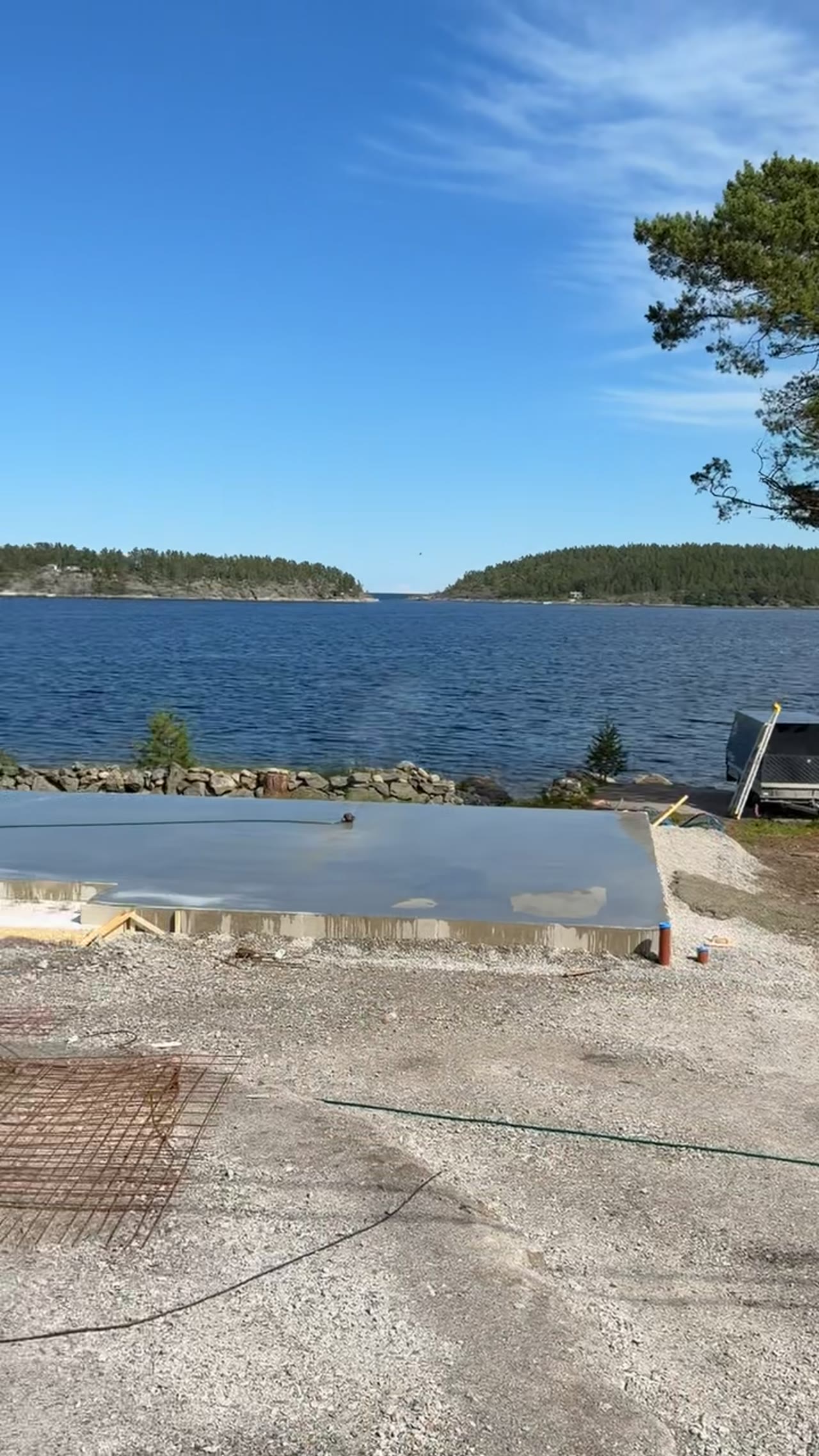 Nybygge med gjuten grund vid vatten med utsikt över skogklädda öar